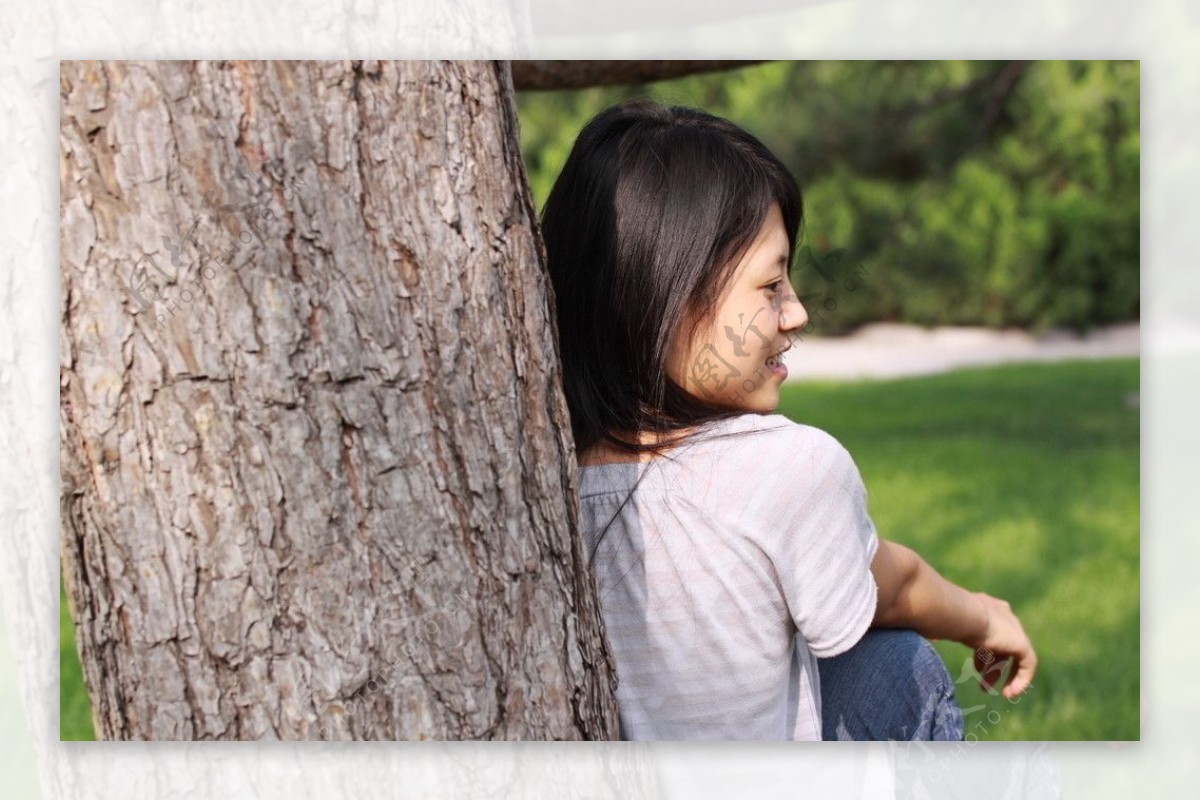 坐在草地上靠着松树的女学生图片