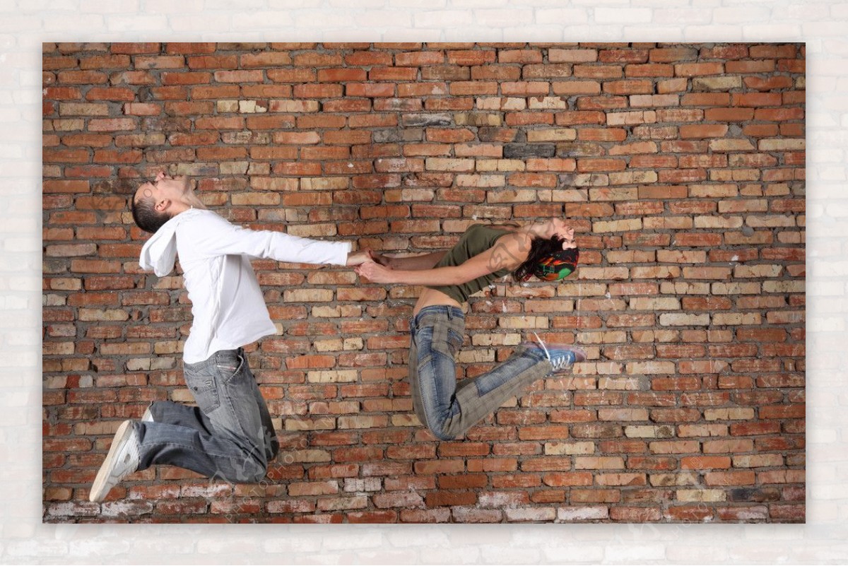 砖头墙前面跳跃的人图片