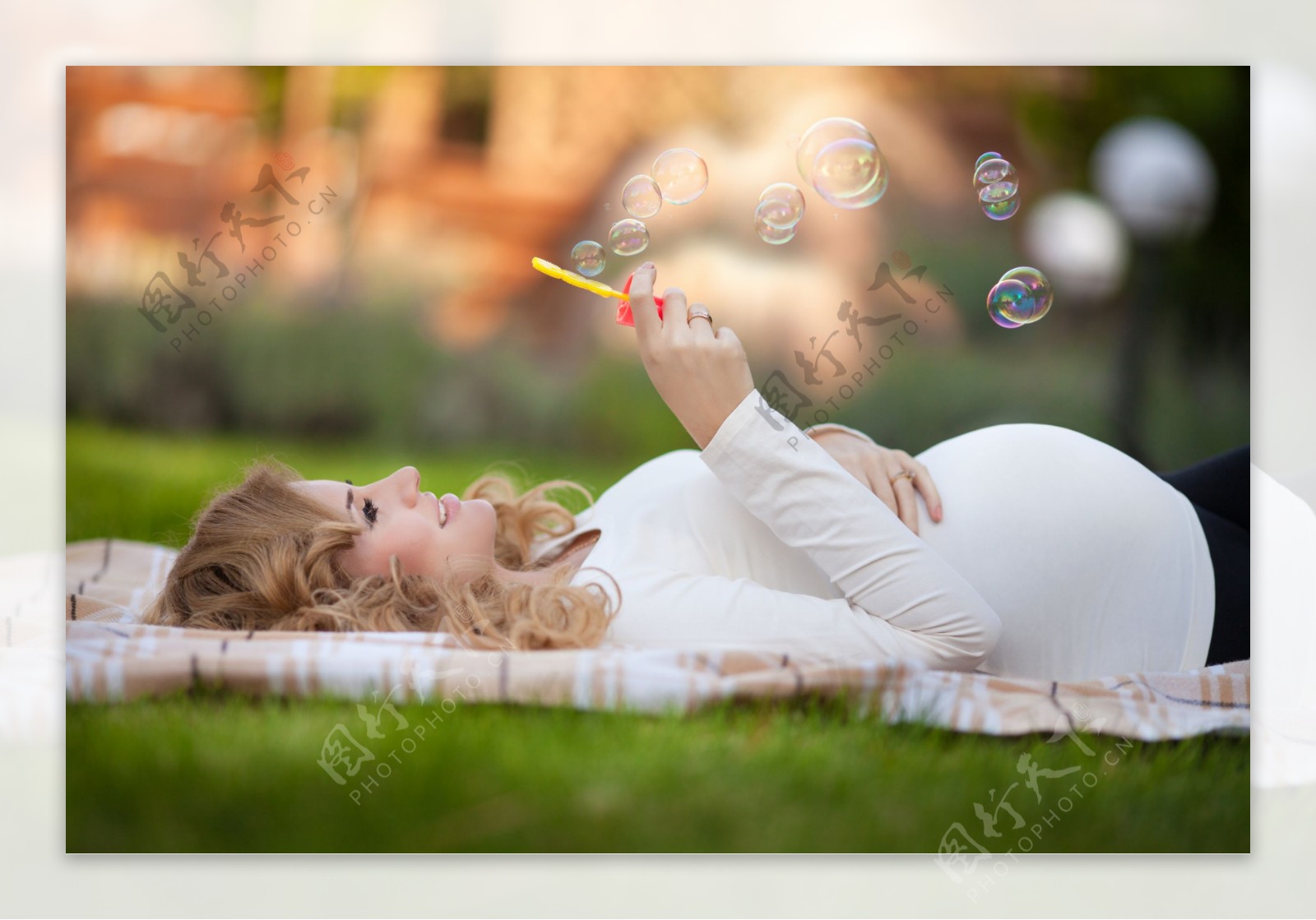 躺在草地上吹泡泡的大肚子妈妈图片