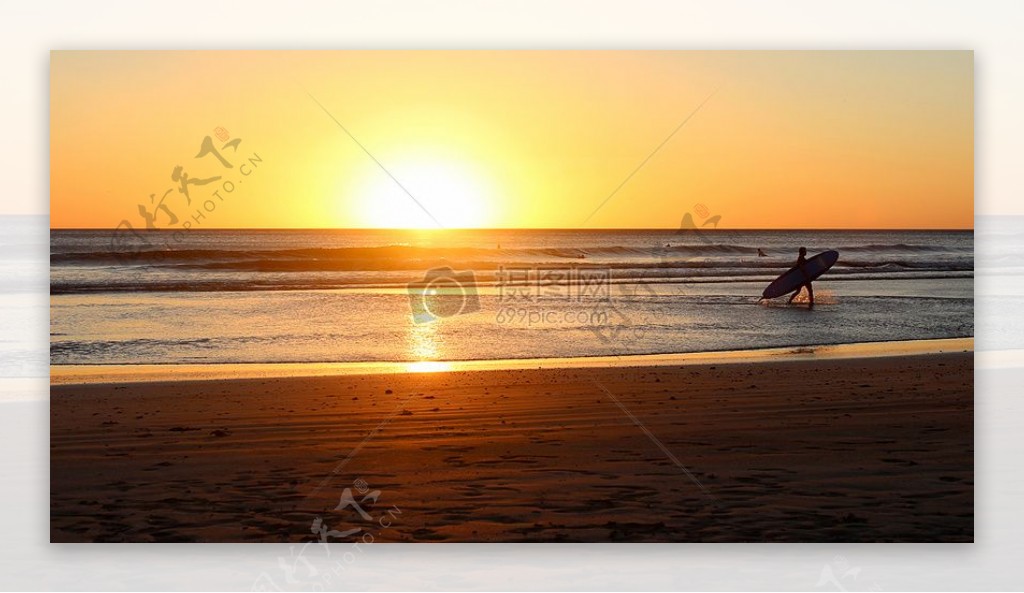 人在海上日落时携带冲浪板
