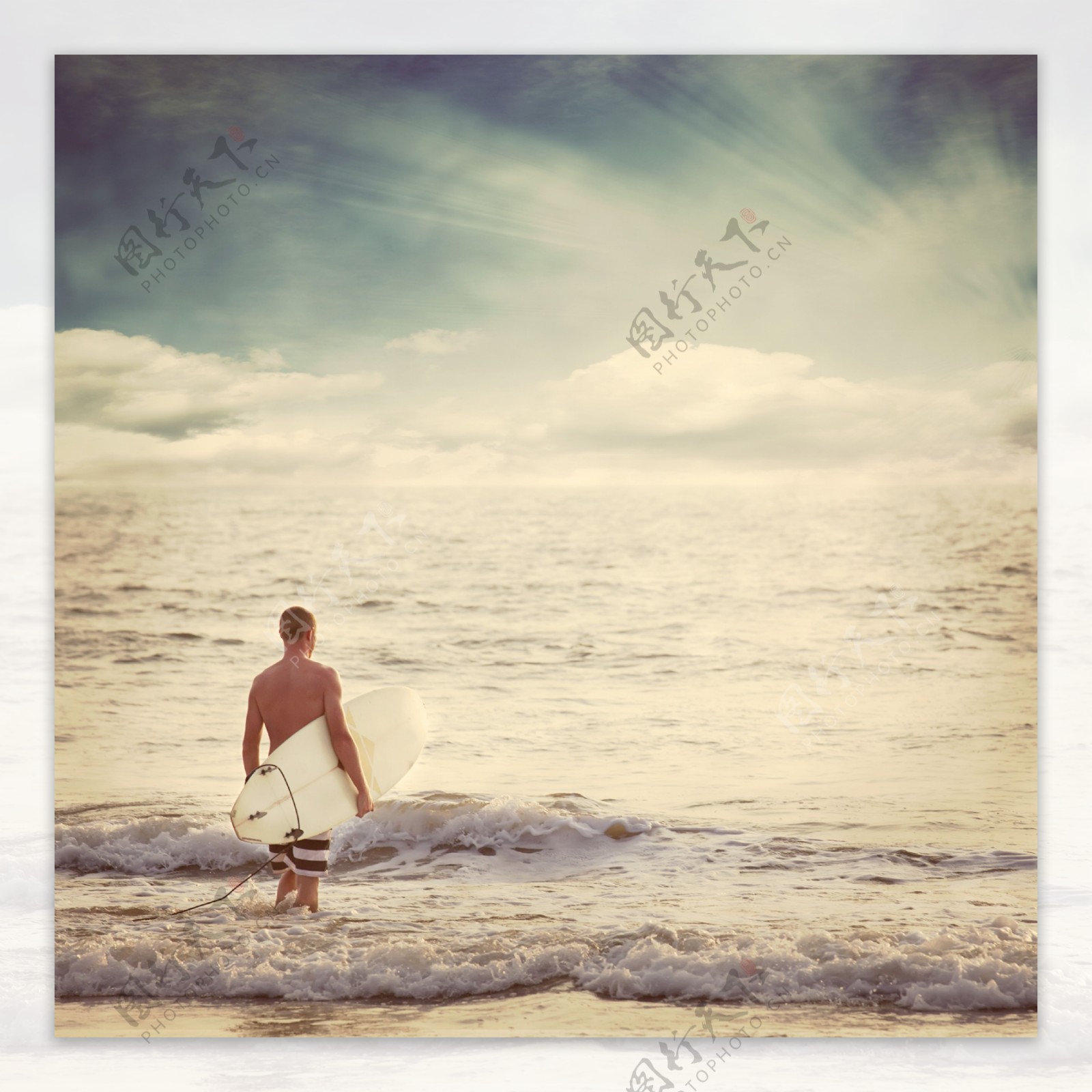 海水中拿着冲浪板的男人图片