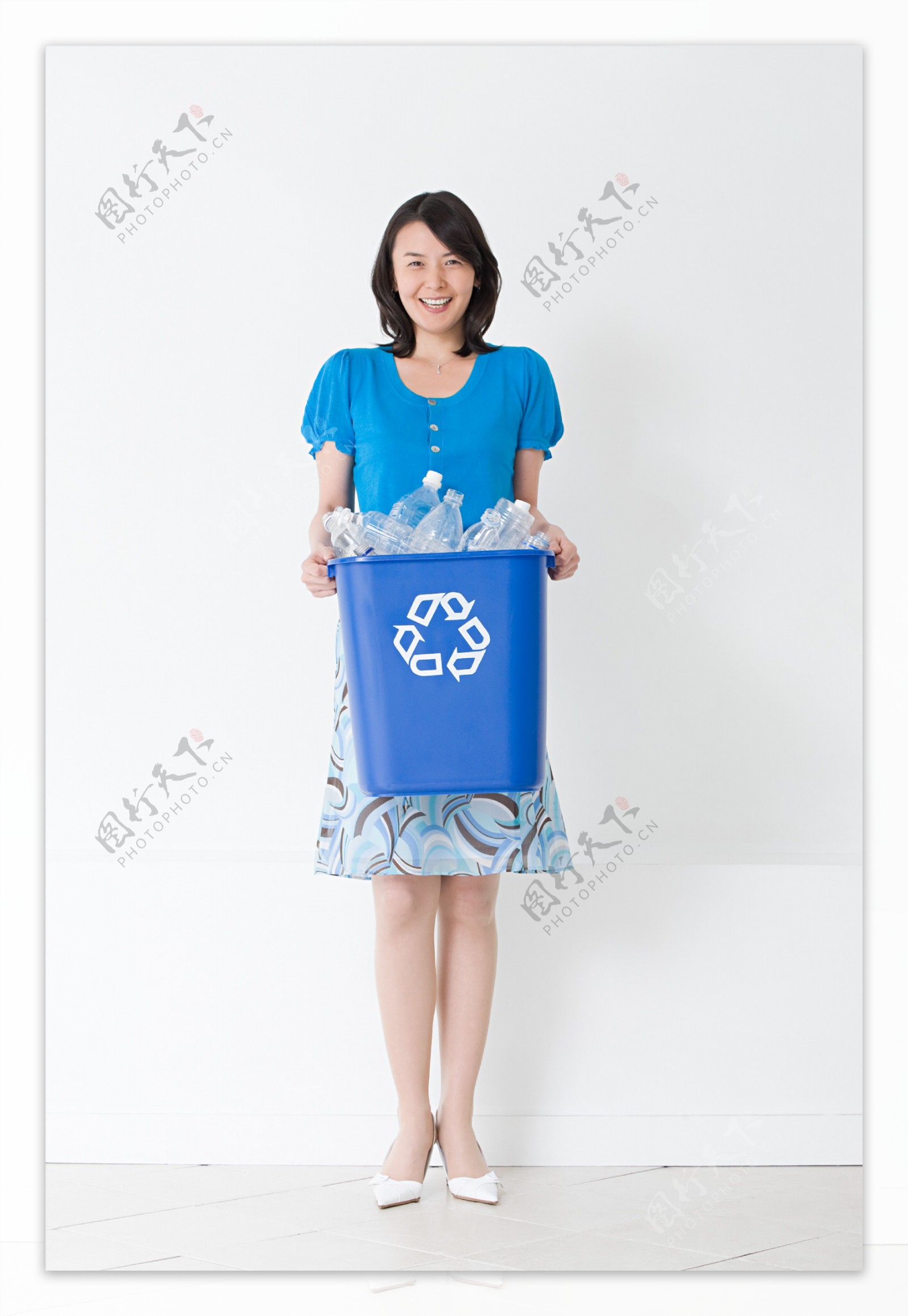 端着一桶塑料瓶微笑的女人图片