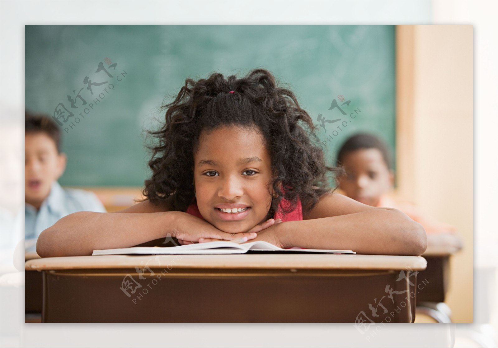 教室里趴在课桌上微笑的小学生图片